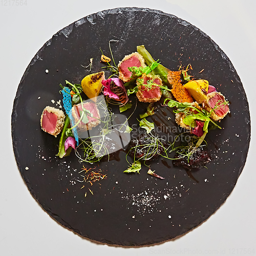 Image of Close up of rare seared Ahi tuna slices with fresh vegetable salad on a plate.