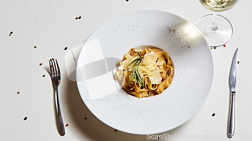 Image of Close-up italian pasta plate with grated parmesan cheese and basil leaf