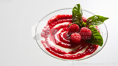 Image of Delicious Italian dessert Panna Cotta with raspberry in small transparent glass