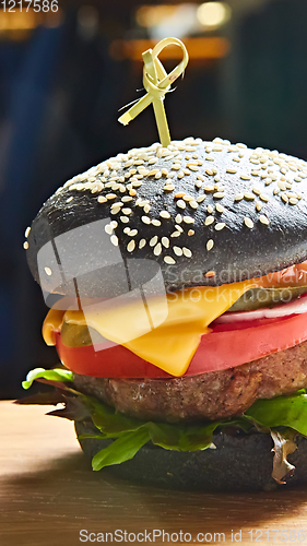 Image of Japanese Black Burger with Cheese. Cheeseburger from Japan with black bun on dark background.