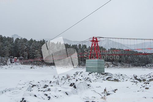 Image of Suspension hanging bridge above winter frozen river