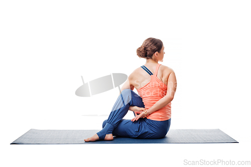 Image of Woman practices yoga asana Ardha matsyendrasana