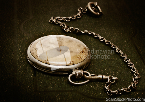 Image of Old clock with chain lying on rough green surface
