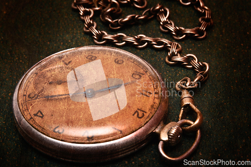 Image of Old clock with chain lying on rough green surface