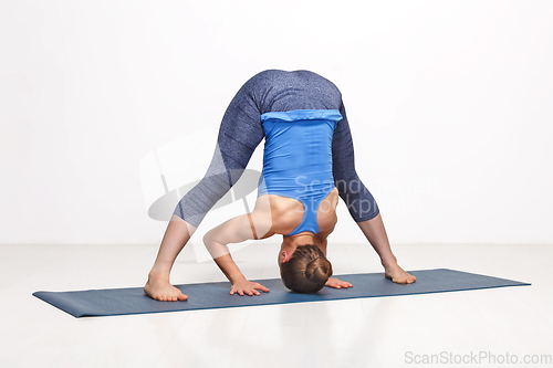 Image of Woman doing yoga asana Prasarita padottanasana