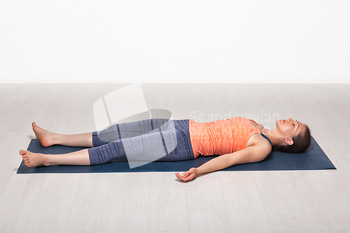 Image of Sporty fit girl relaxes in yoga asana Savasana