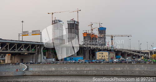 Image of Many of cranes. Tower cranes against blue sky, with clouds