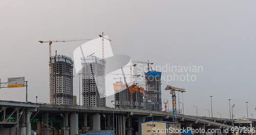 Image of Many of cranes. Tower cranes against blue sky, with clouds