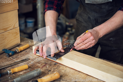 Image of The worker makes measurements of a wooden board