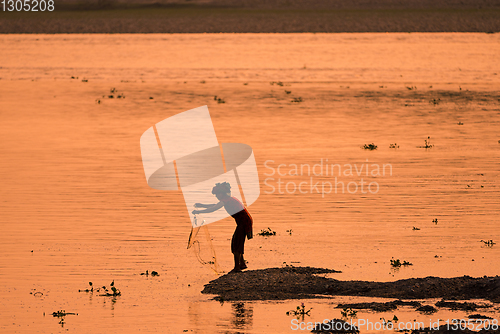 Image of Asian Woman fishing in the river, silhouette at sunset