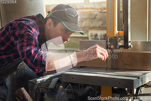 Image of Construction worker cutting wooden board