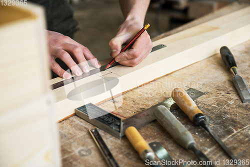 Image of The worker makes measurements of a wooden board