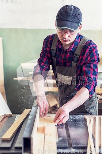 Image of Construction worker cutting wooden board