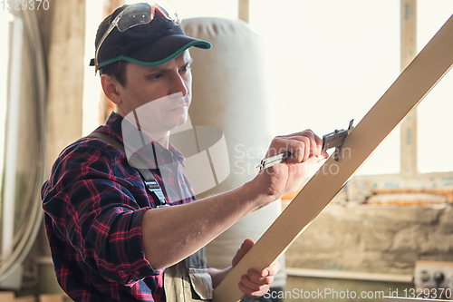 Image of The worker makes measurements of a wooden board