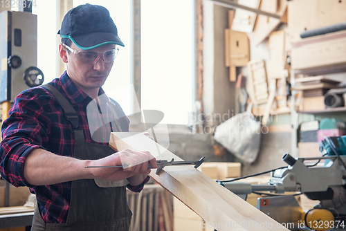 Image of The worker makes measurements of a wooden board