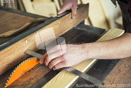 Image of Construction worker cutting wooden board