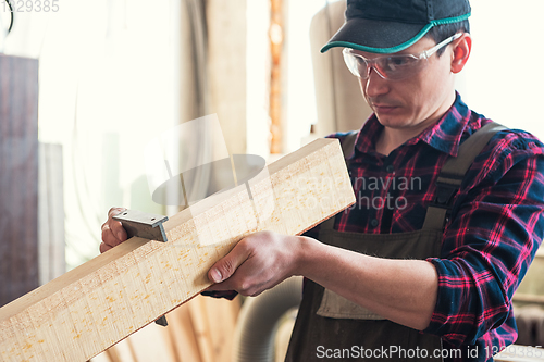 Image of The worker makes measurements of a wooden board