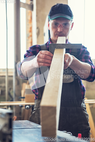 Image of The worker makes measurements of a wooden board