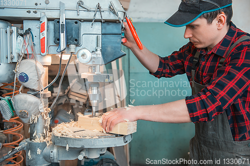 Image of Carpenters with electric drill machine drilling wooden board