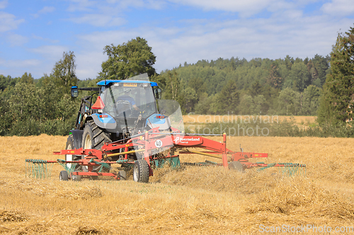 Image of Farm Tractor and Twin Rotary Rake Working in Field