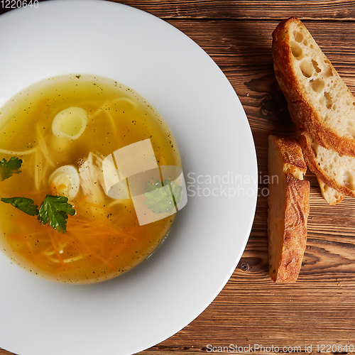 Image of Meat broth with chicken meat, egg and parsley in a white bowl, b