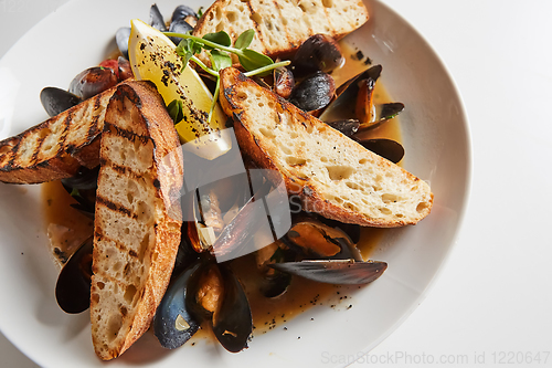 Image of Seafood. Mussels in wine with croutons and lemon. Clams in the shells.