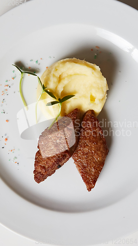 Image of delicious mashed potatoes sprinkled with greens, juicy meat cutl