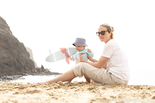 Image of Mother playing his infant baby boy son on sandy beach enjoying summer vacationson on Lanzarote island, Spain. Family travel and vacations concept.