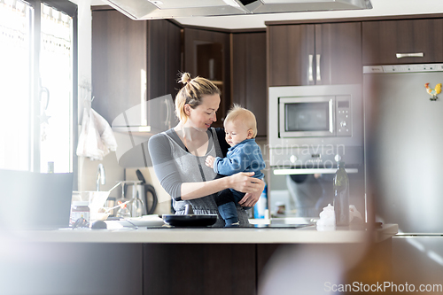 Image of Happy mother and little infant baby boy making pancakes for breakfast together in domestic kitchen. Family, lifestyle, domestic life, food, healthy eating and people concept.