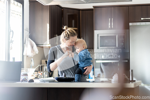 Image of Happy mother and little infant baby boy making pancakes for breakfast together in domestic kitchen. Family, lifestyle, domestic life, food, healthy eating and people concept.