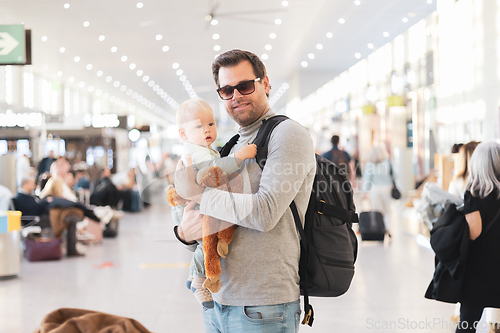 Image of Father traveling with child, holding his infant baby boy at airport terminal waiting to board a plane. Travel with kids concept.