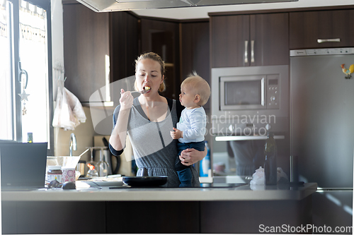 Image of Happy mother and little infant baby boy prepering healthy breakfast together in domestic kitchen. Family, lifestyle, domestic life, food, healthy eating and people concept.