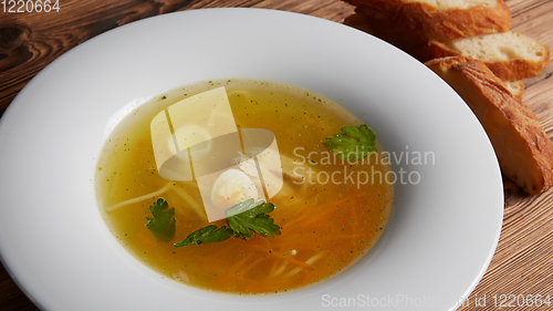 Image of Meat broth with chicken meat, egg and parsley in a white bowl, b