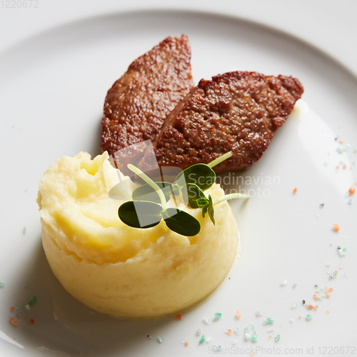 Image of delicious mashed potatoes sprinkled with greens, juicy meat cutl