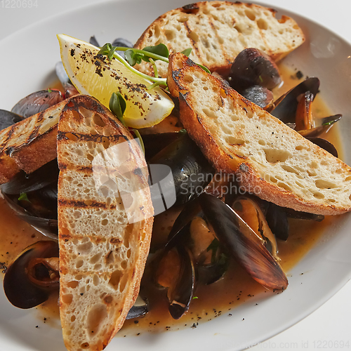 Image of Seafood. Mussels in wine with croutons and lemon. Clams in the shells.