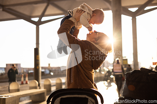 Image of Motherat happily holding and lifting his infant baby boy child in the air after being rejunited in front of airport terminal station. Baby travel concept.