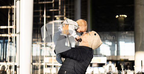 Image of Father happily holding and lifting his infant baby boy child in the air after being rejunited in front of airport terminal station. Baby travel concept.