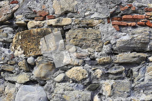 Image of Old wall from stones of various shapes and red bricks