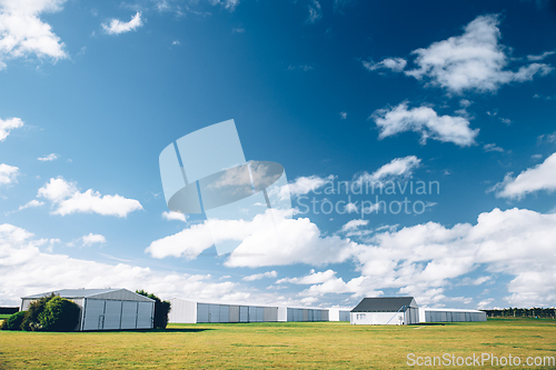 Image of Steel barn on a farm with cloudy blue sky.