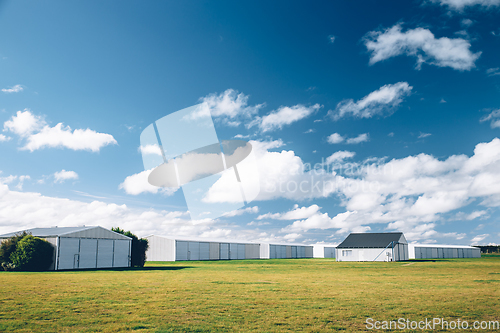 Image of Steel barn on a farm with cloudy blue sky.