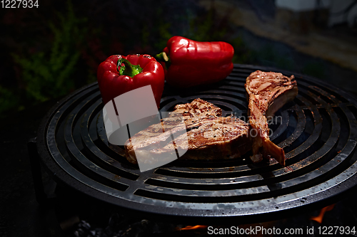 Image of Tomahawk rib beef steak and T-bone on hot black grill.