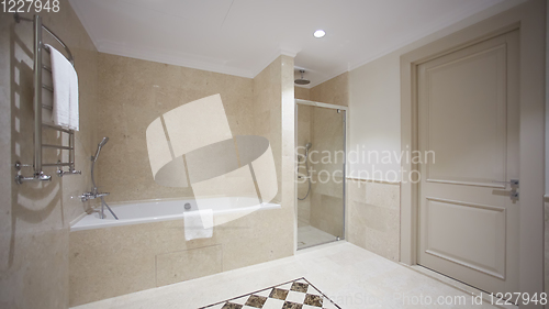 Image of Nice bathroom in a modern style with gray tiled walls. There is a white bath with a glass partition, shower, mirrors, light sink, toilet and a bidet, luminous lamps