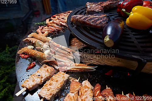 Image of Tomahawk rib beef steak and T-bone on hot black grill.