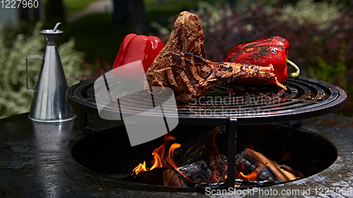 Image of Tomahawk rib beef steak and T-bone on hot black grill.