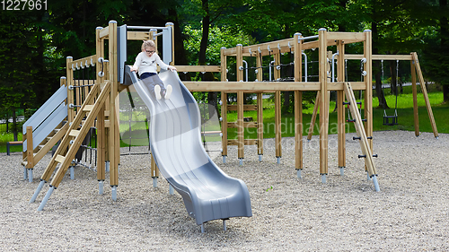 Image of Little girl on a playground. Child playing outdoors in summer. Kids play on school yard.