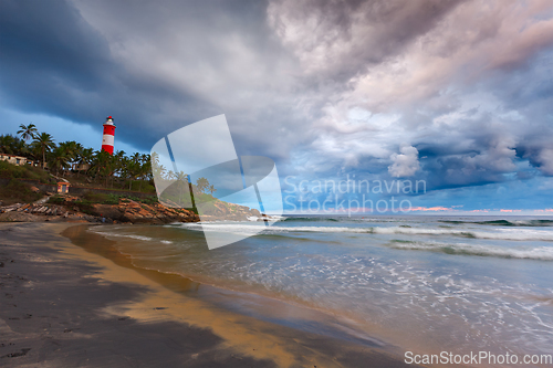 Image of Gathering storm on beach and lighthouse on sunset. Kerala, India