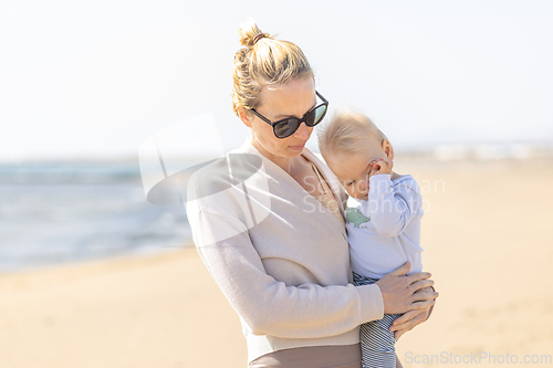 Image of Mother holding and carrying his infant baby boy son on sandy beach enjoying summer vacationson on Lanzarote island, Spain. Family travel and vacations concept.