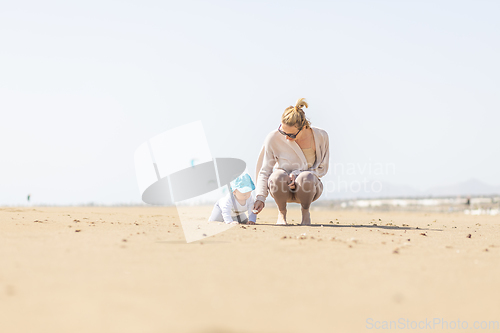 Image of Mother playing his infant baby boy son on sandy beach enjoying summer vacationson on Lanzarote island, Spain. Family travel and vacations concept.