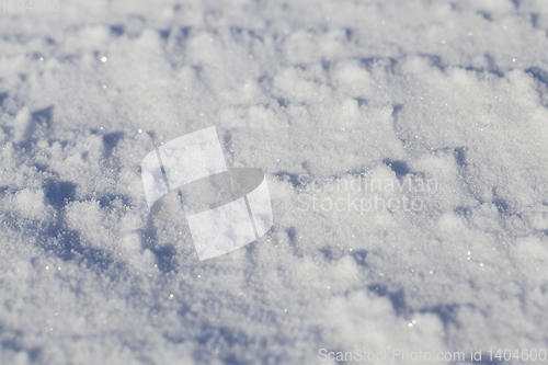 Image of land covered with snow - white snow after snow had fallen and covered the land in the agricultural field. Photo closeup in the winter season, a small depth of field. On visible surface roughness snow