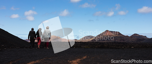 Image of Tourists visiting volcanic landscape of Timanfaya National Park in Lanzarote. Popular touristic attraction in Lanzarote island, Canary Islands, Spain.